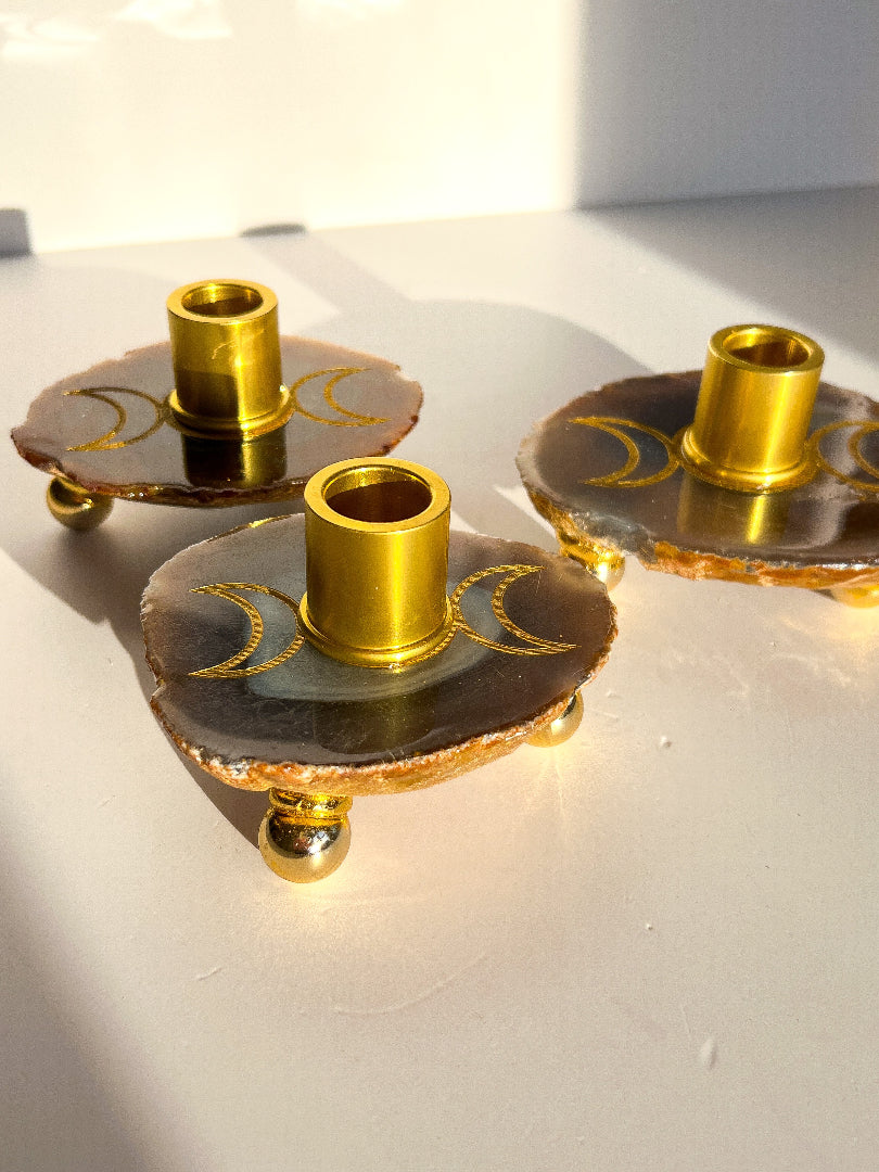 Three gold candle holders on a white surface