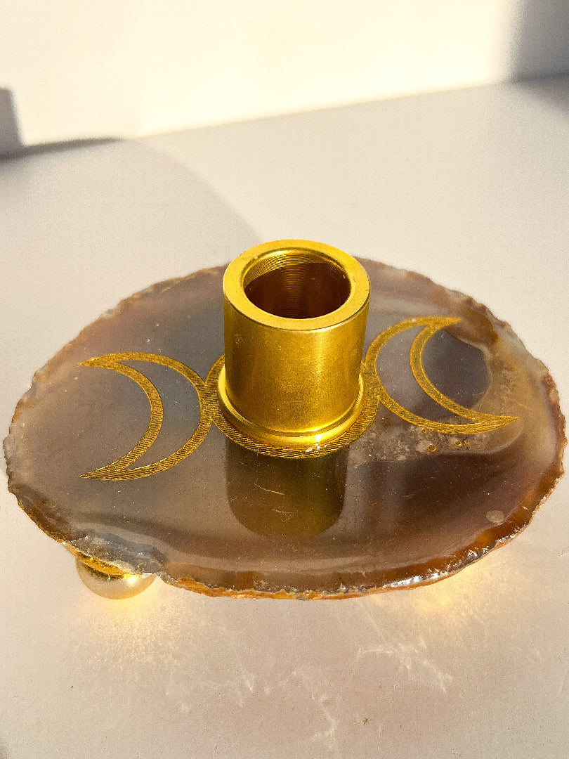 Gold candle holder on a decorative stone base with moon designs