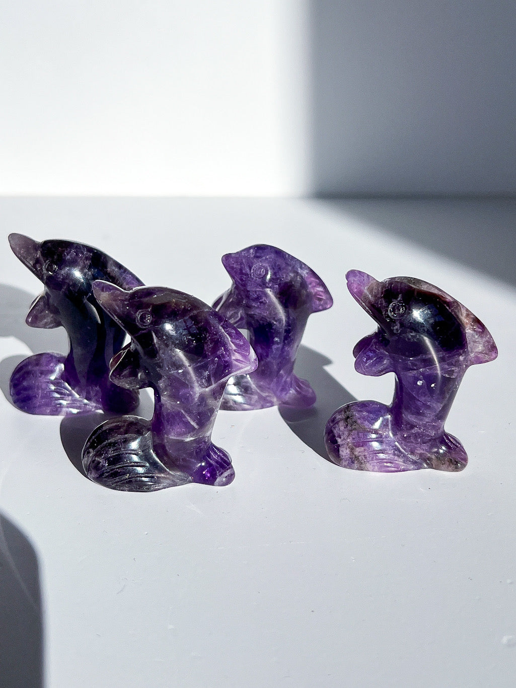 Set of purple crystal dolphins on a white surface with a light gray background