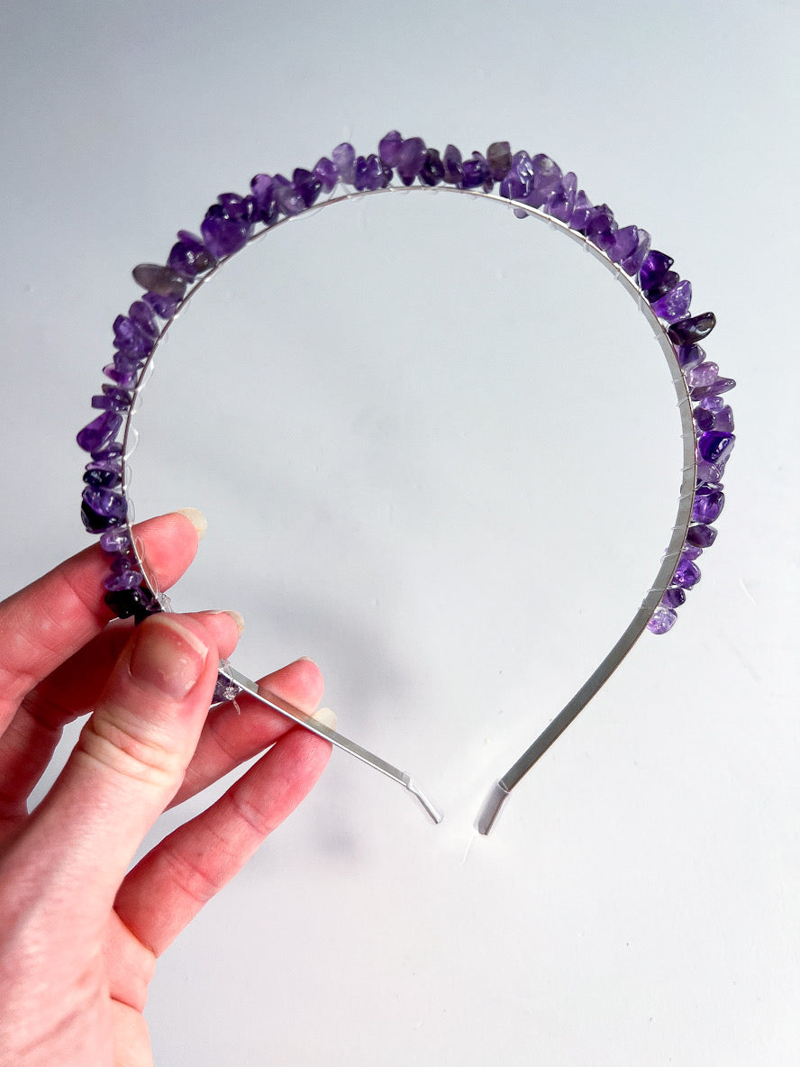 Amethyst crystal chip headband in hand with white background.