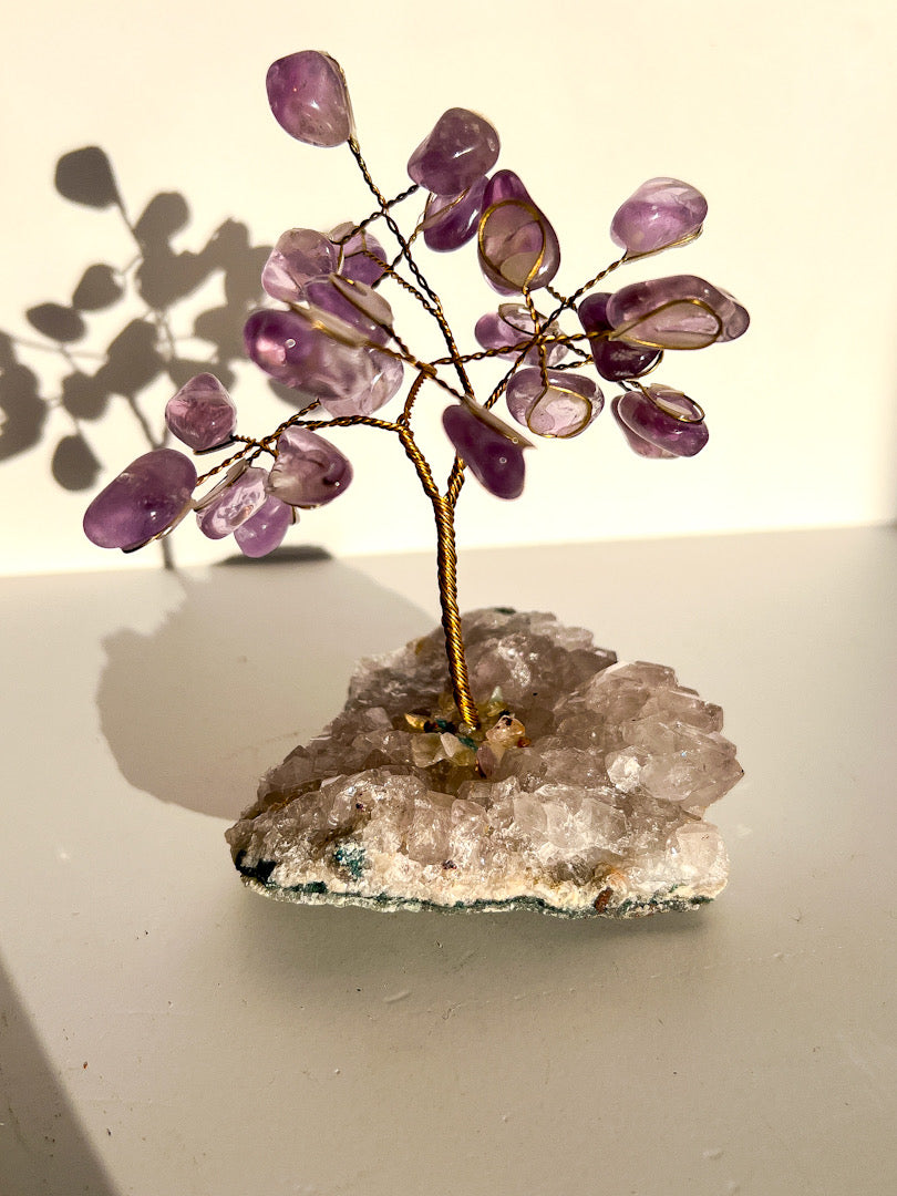 Amethyst crystal tree on a clear crystal base with a neutral background