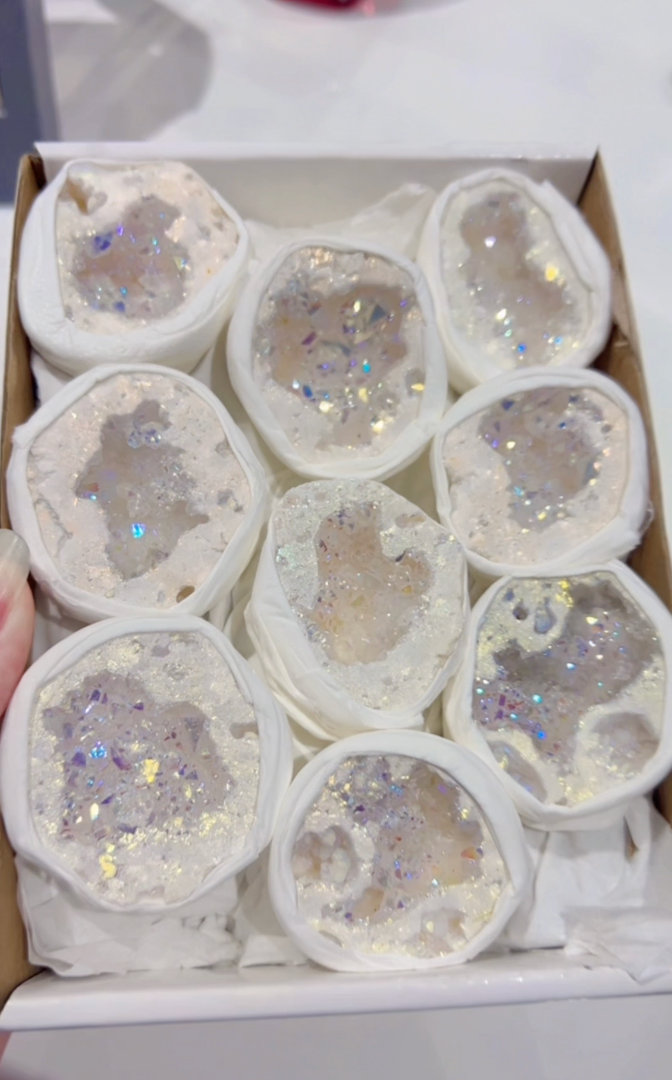 Box of white crystal geodes with glittery centres on a white background