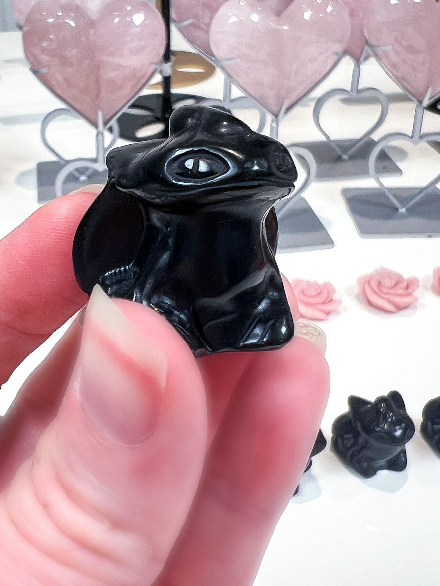 Black dragon held in a hand with a decorative background
