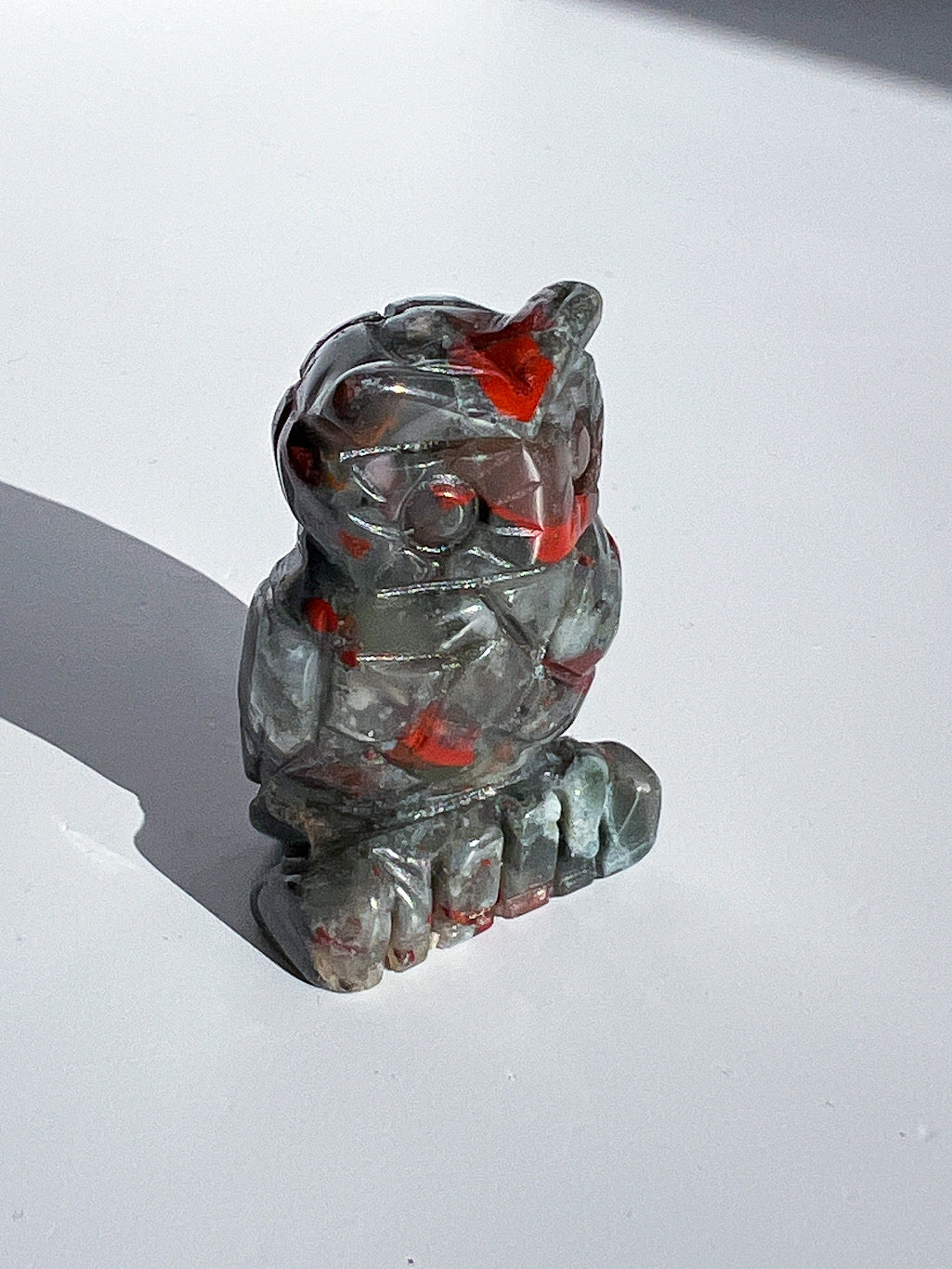 Crystal figurine with red inclusions on a white surface
