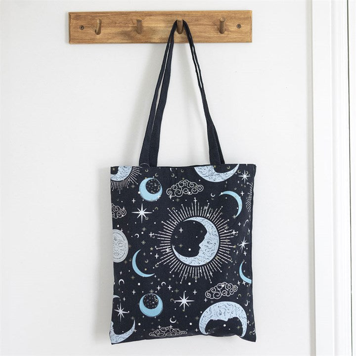 Blue Celestial Print Tote Bag hanging off a brown peg next to a white background.