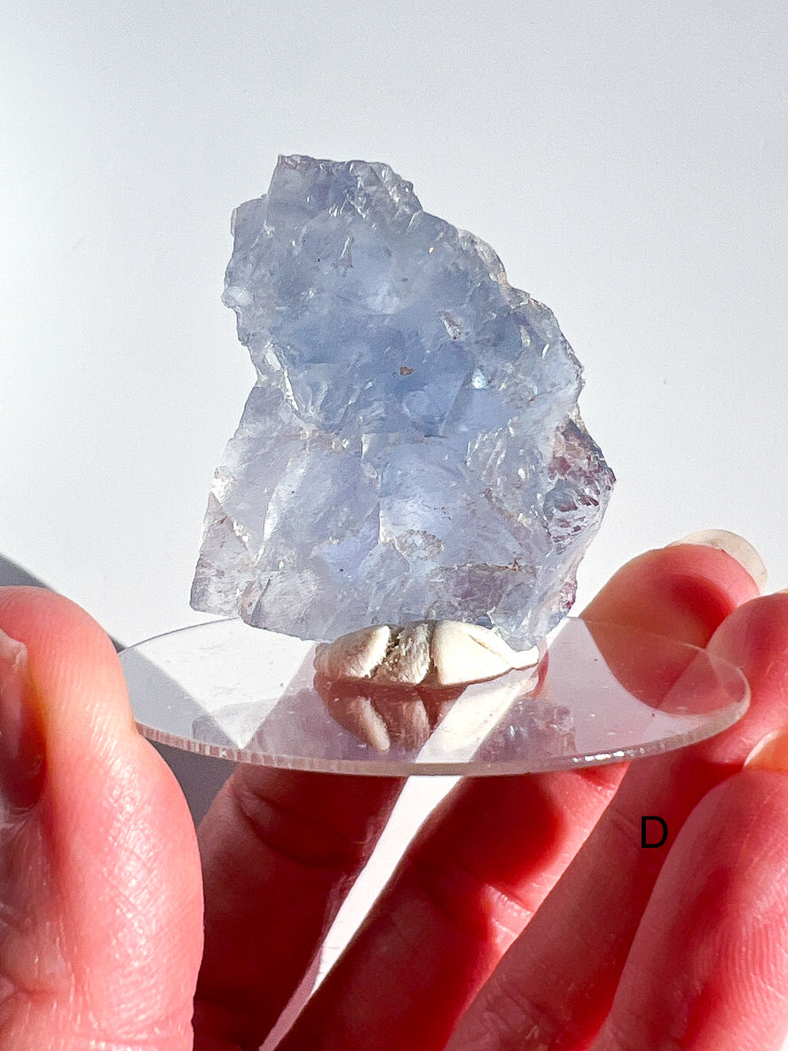 Pale blue crystal held between two hands against a light background