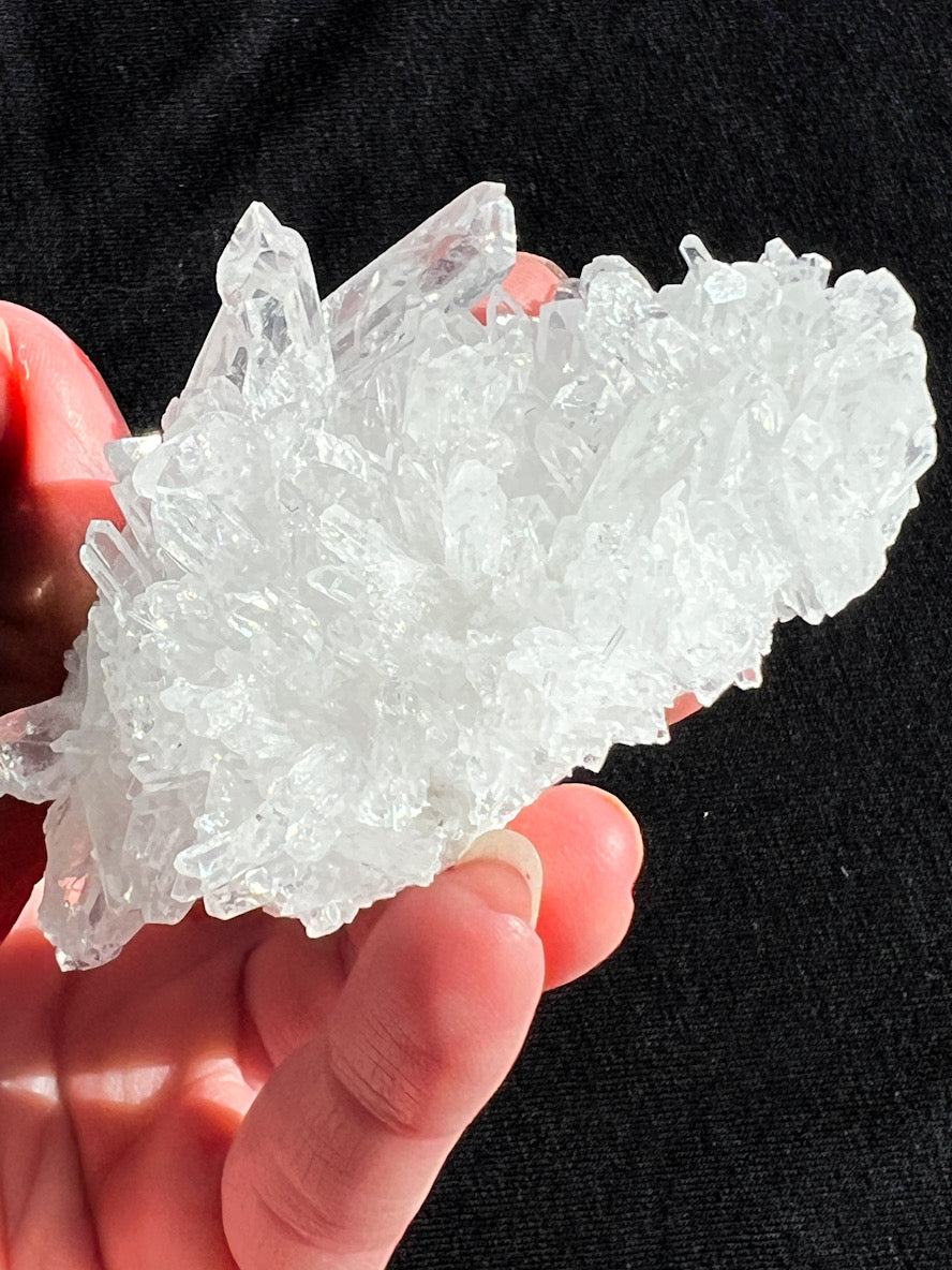Hand holding a large crystal formation against a black background