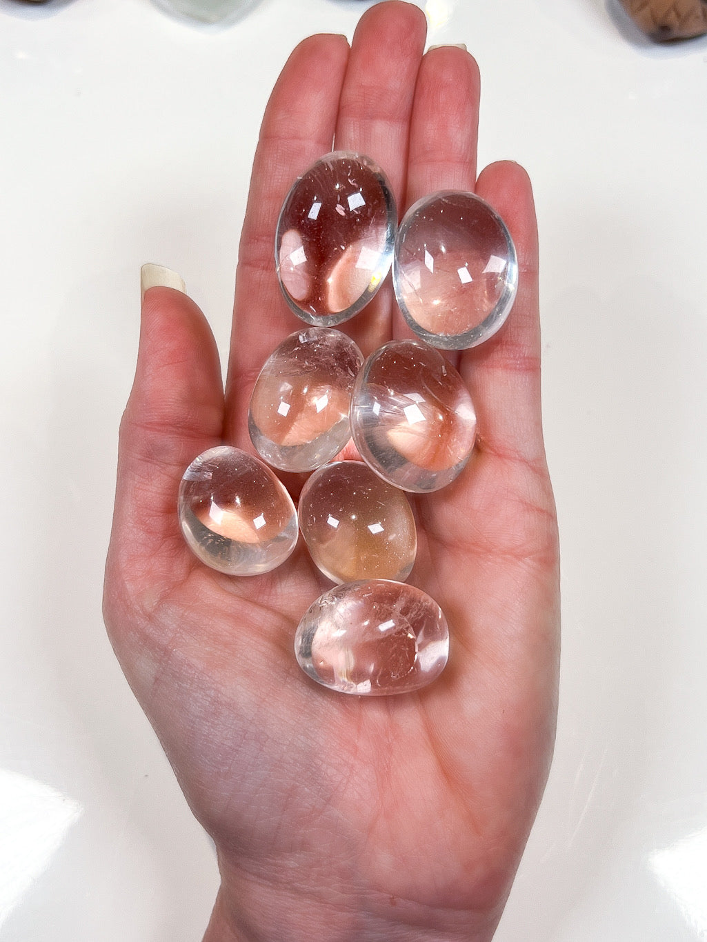 Hand holding clear crystal tumbles on a white background