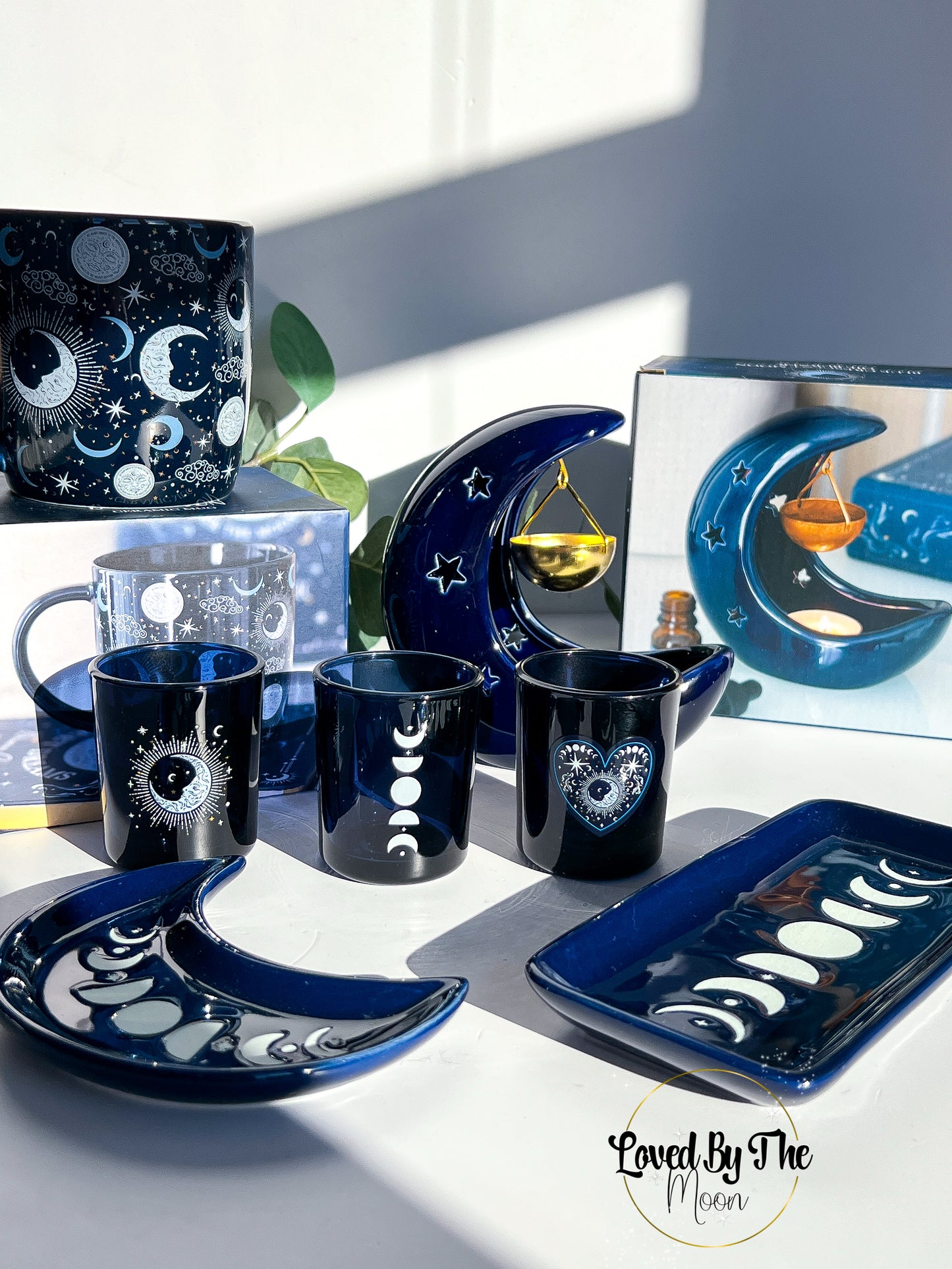 Table setting with moon-themed mugs, plates, and decor items on a white surface.