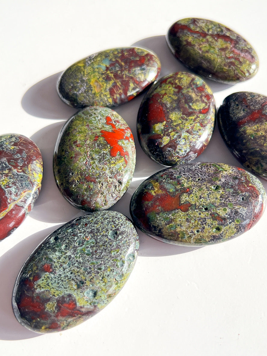 Dragon Bloodstone Palm Stones on a white table.