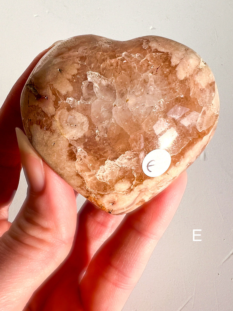 Heart-shaped crystal held in a hand against a light background