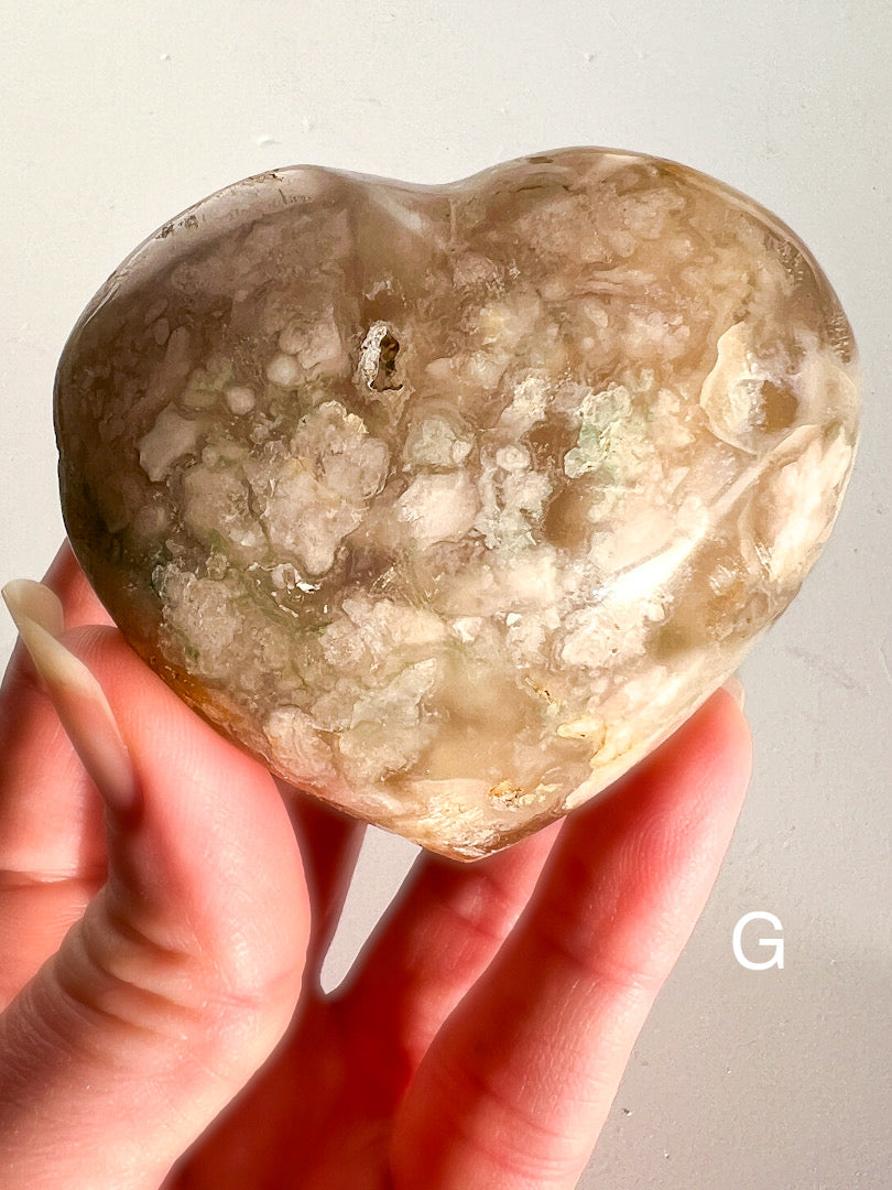 Heart-shaped stone held in a hand against a plain background