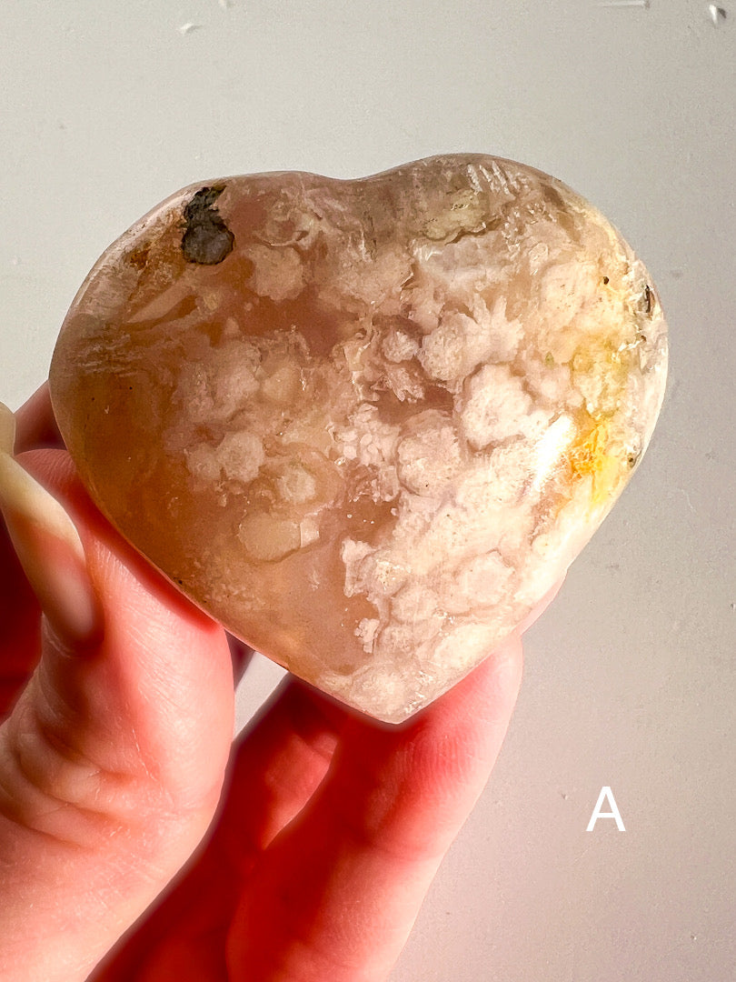 Heart-shaped stone held in a hand against a neutral background