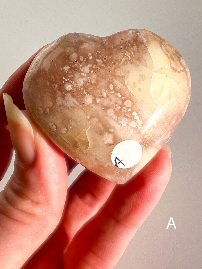 Heart-shaped stone held in a hand with a neutral background