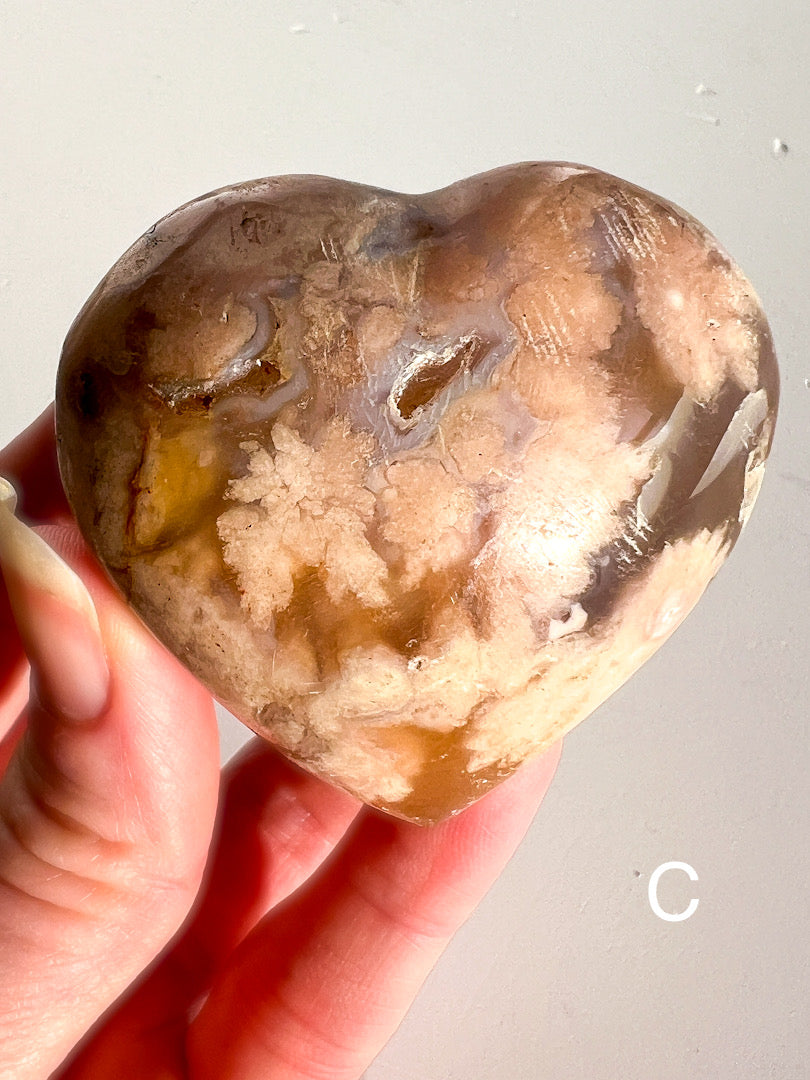 Heart-shaped stone held in a hand against a neutral background