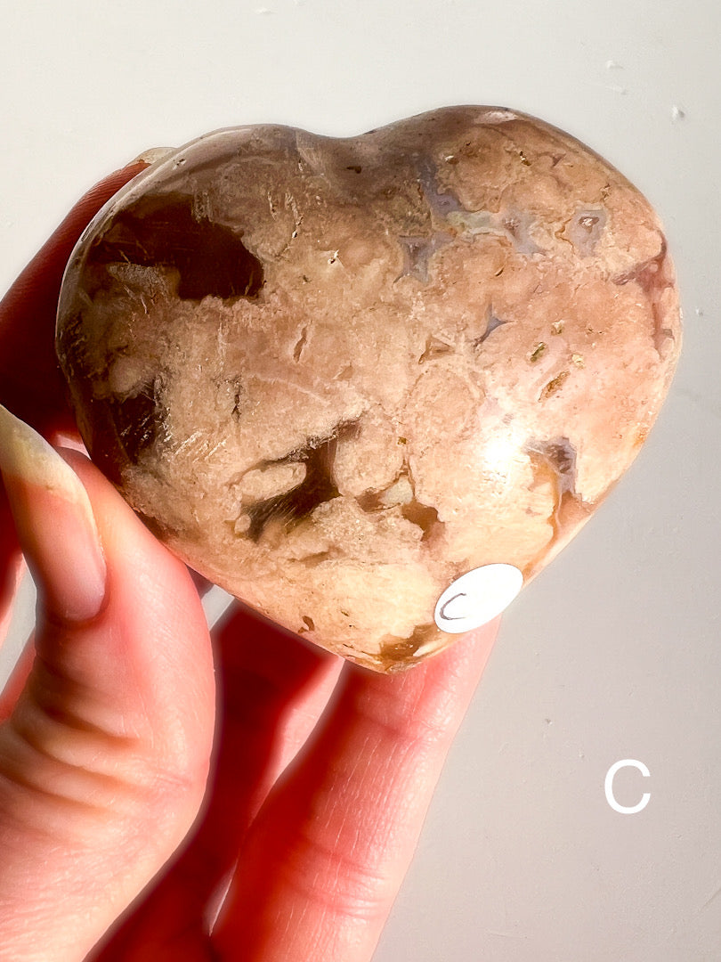 Heart-shaped stone held in a hand against a neutral background