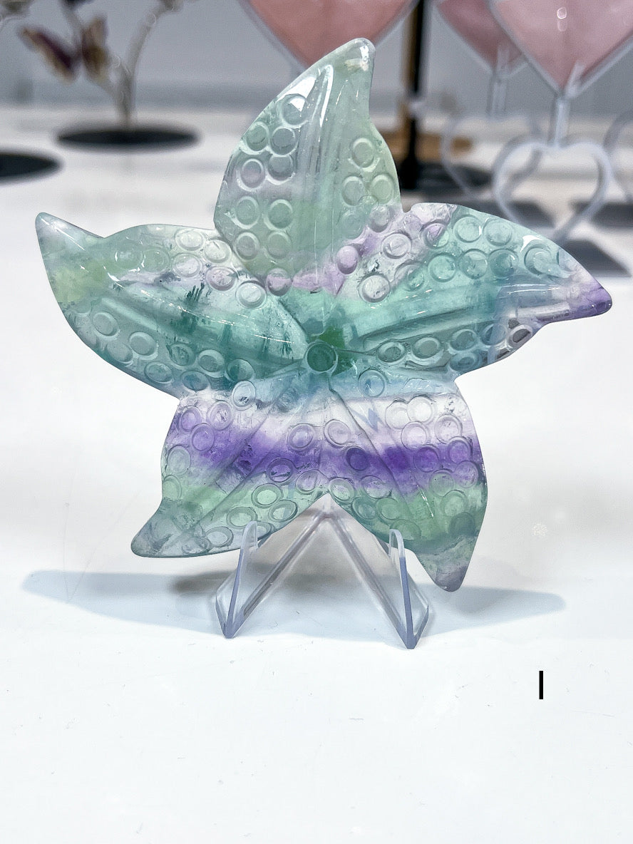 Multicolored starfish-shaped crystal on a stand with a blurred background