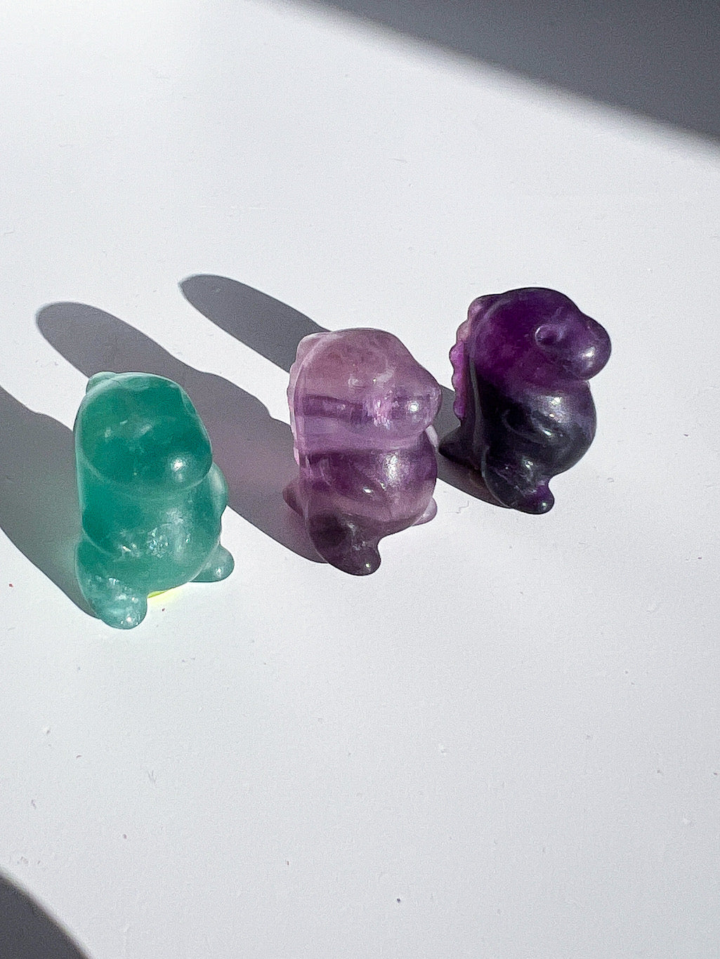 Three crystal animal figurines on a white surface with shadows.