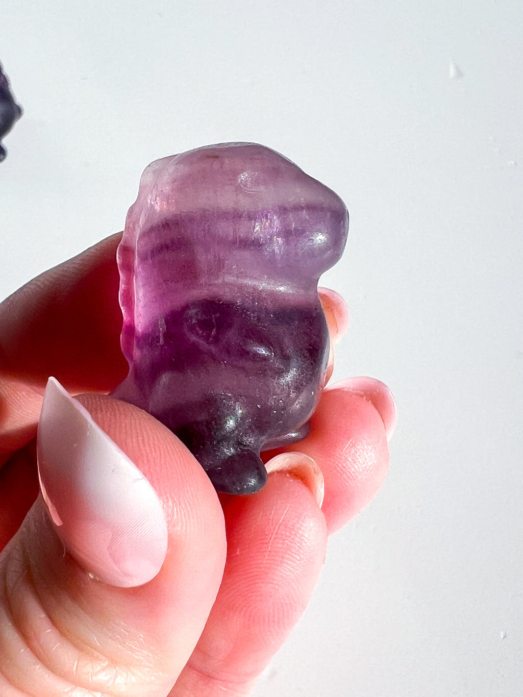 Hand holding a purple crystal with a white background