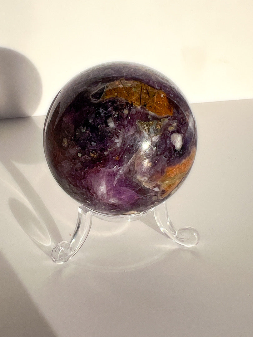 Multicolored crystal sphere on a stand with a white background