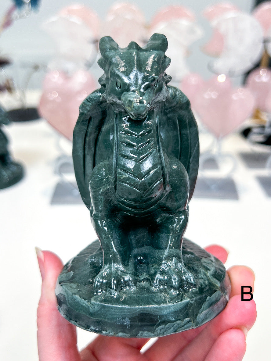 Green dragon figurine held in a hand with a blurred background