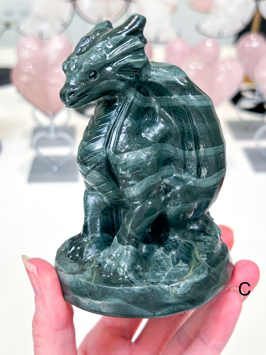 Green stone dragon figurine held in a hand with blurred background
