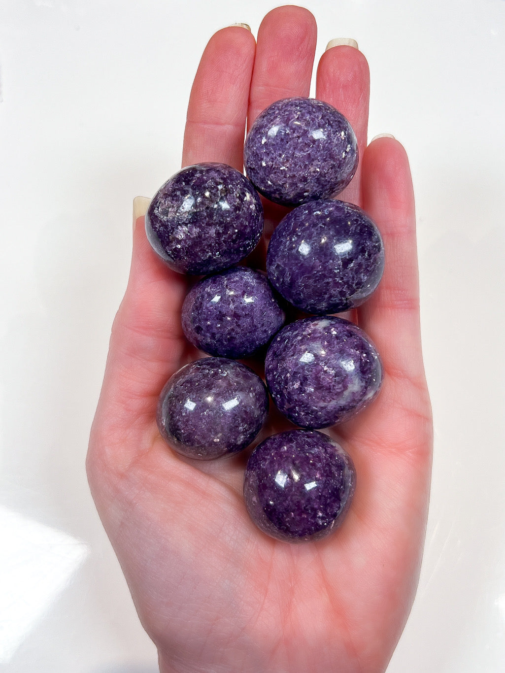 Hand holding purple glittery stones against a white background