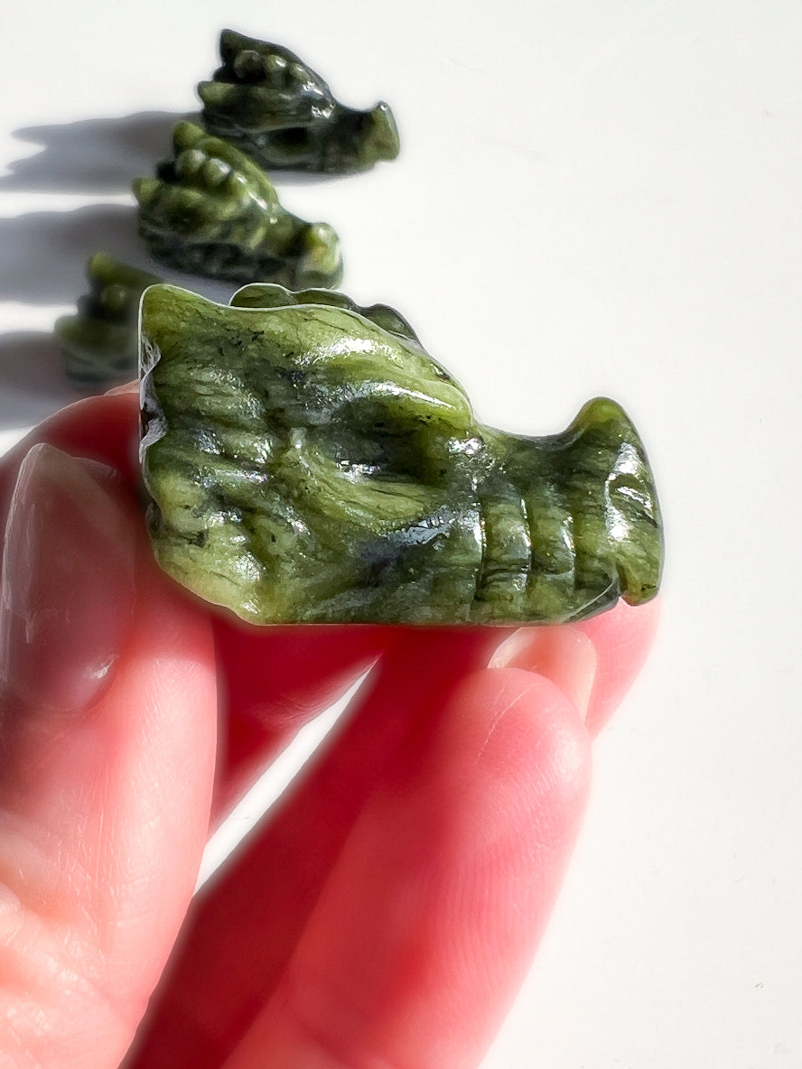 Green dragon shaped object held in a hand with more objects in the background