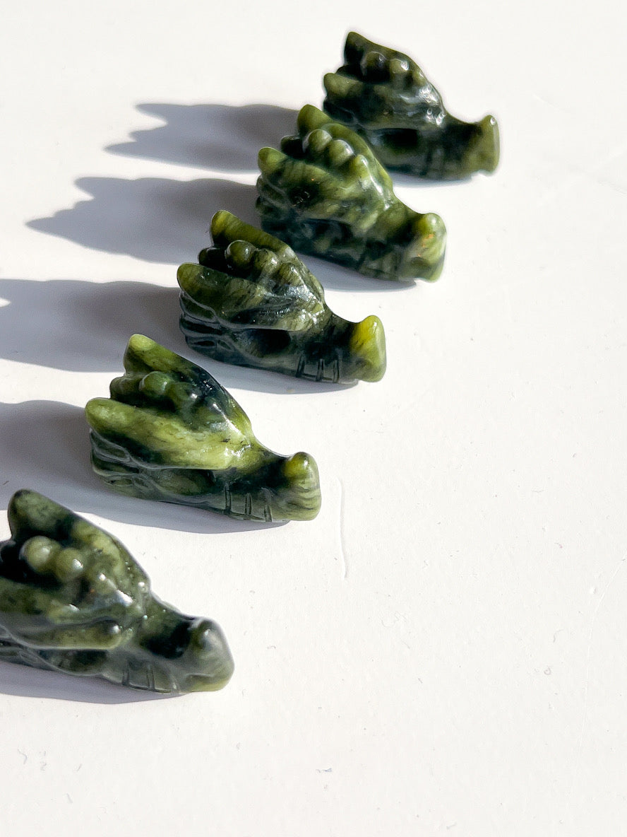 Five green stone carvings of hands on a white background