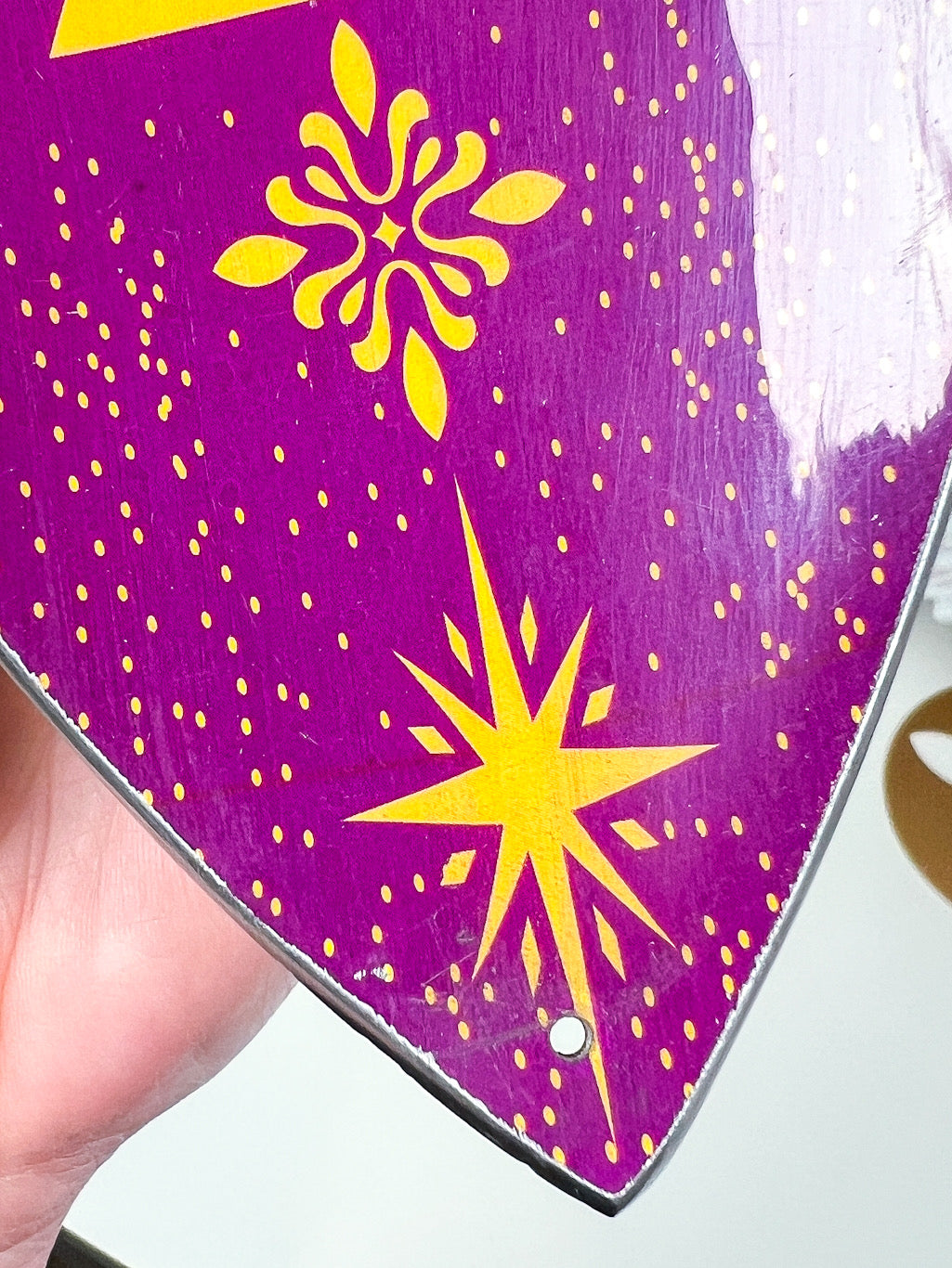purple sun and moon phases incense stick holder in a hand with a blurry white background.
