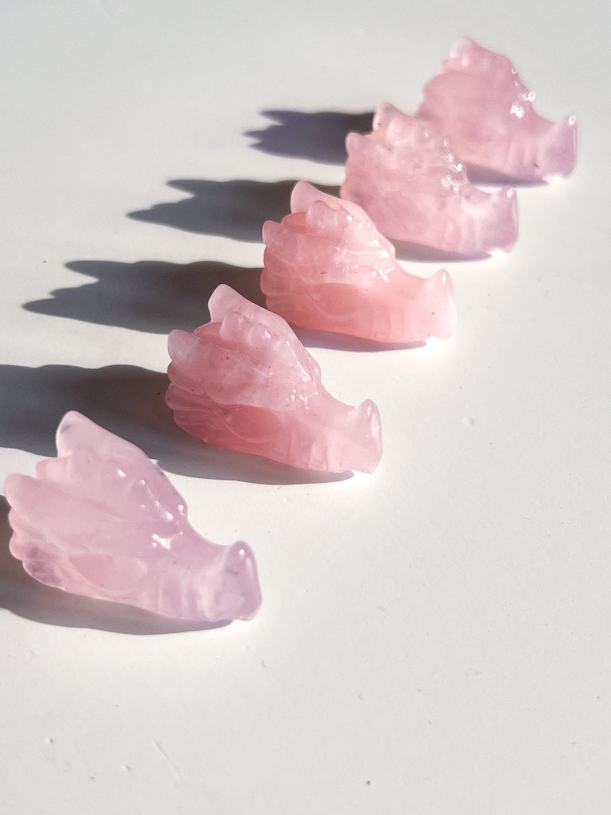 Pink crystal dragon-shaped objects on a white surface