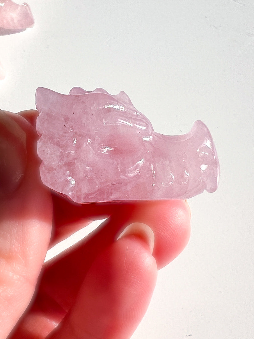 Pink crystal carving held in a hand against a white background