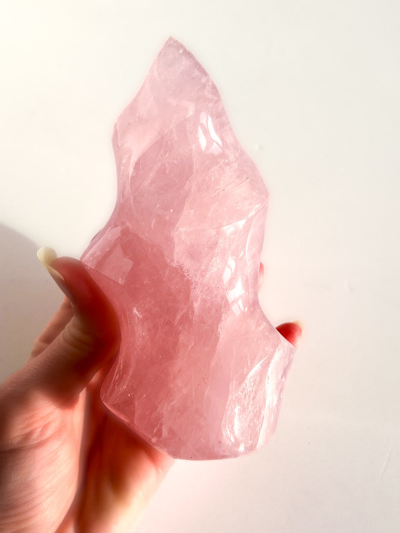 Hand holding a pink crystal against a white background