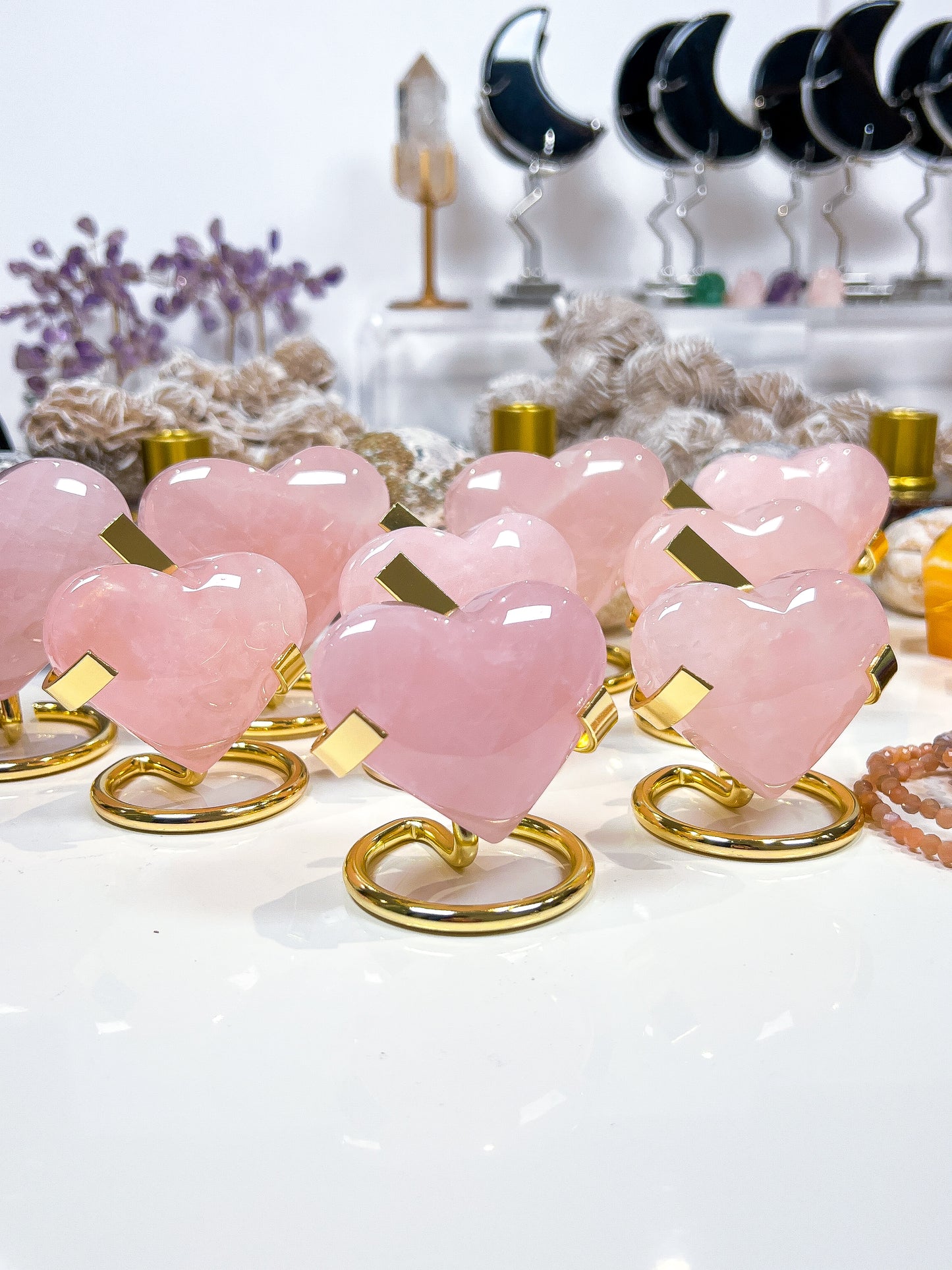 Pink heart-shaped objects on gold stands with a blurred background of decorative items.