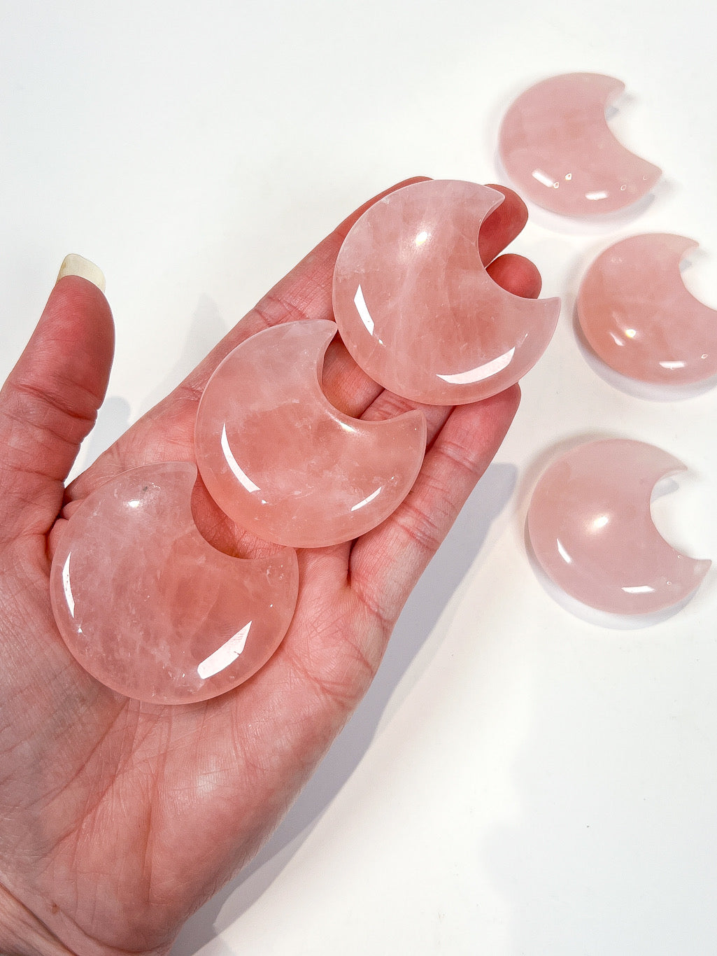 Pink crystal moons on hand with white background
