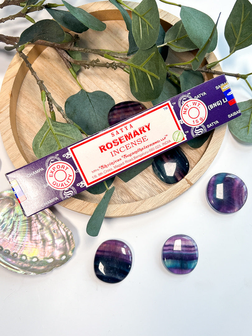 Satya Rosemary incense on wooden tray surrounded by greenery and crystals.