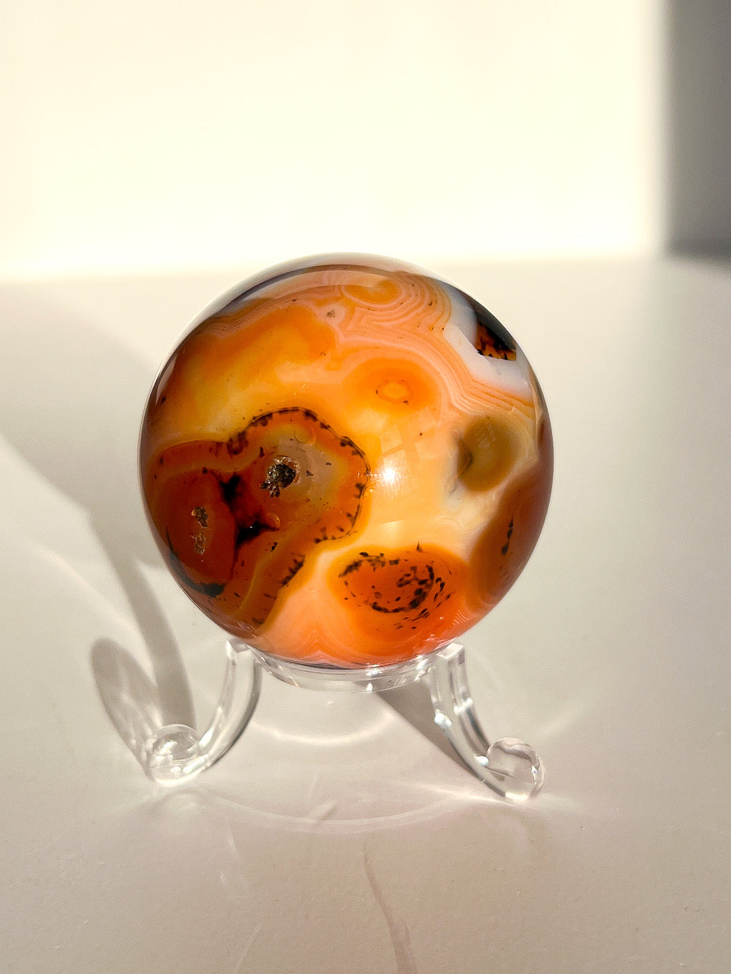 Marbled orange and brown stone on a clear stand against a white background