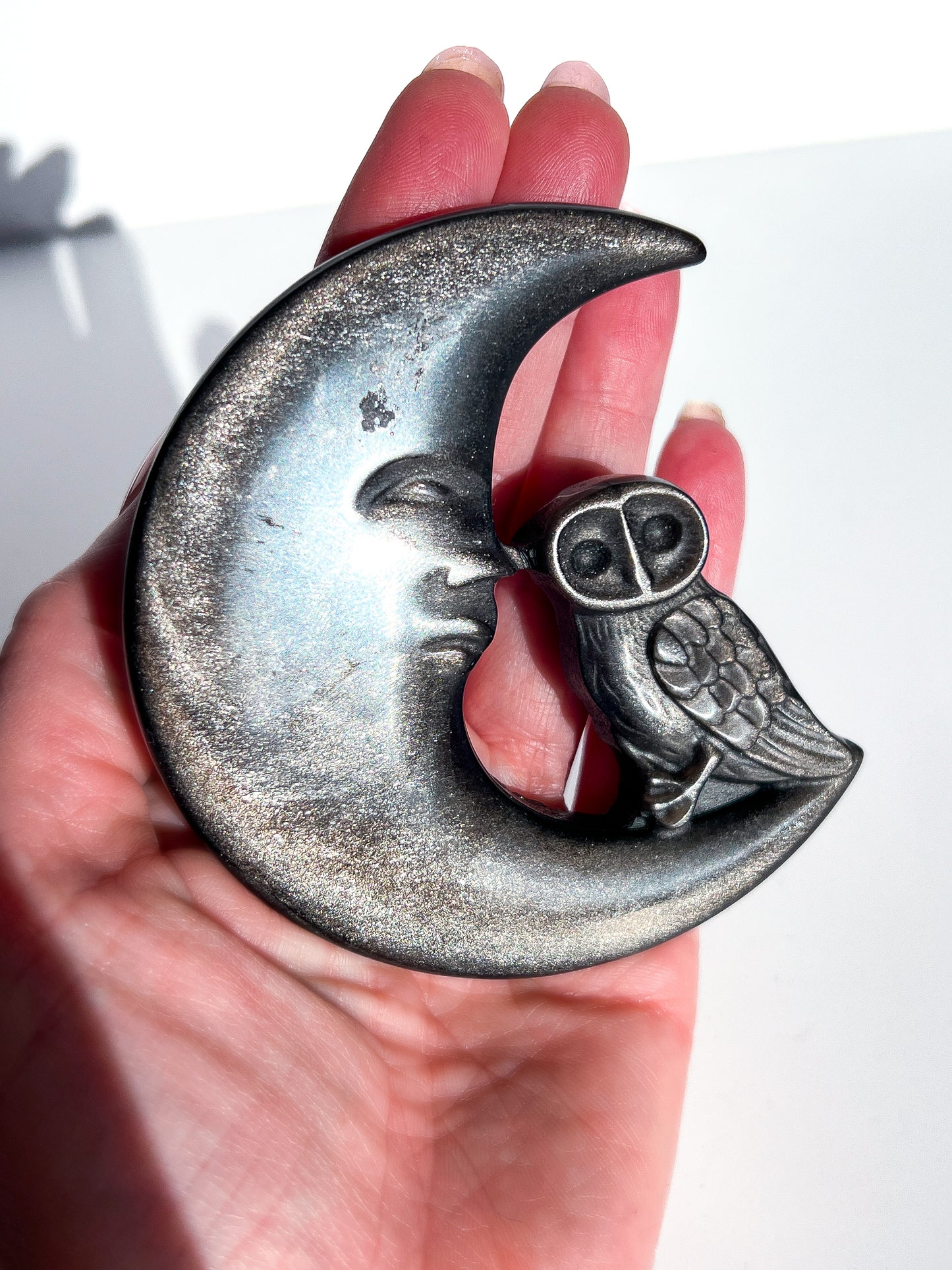 Silver Sheen Obsidian Moon and Owl Carving in hand with white background