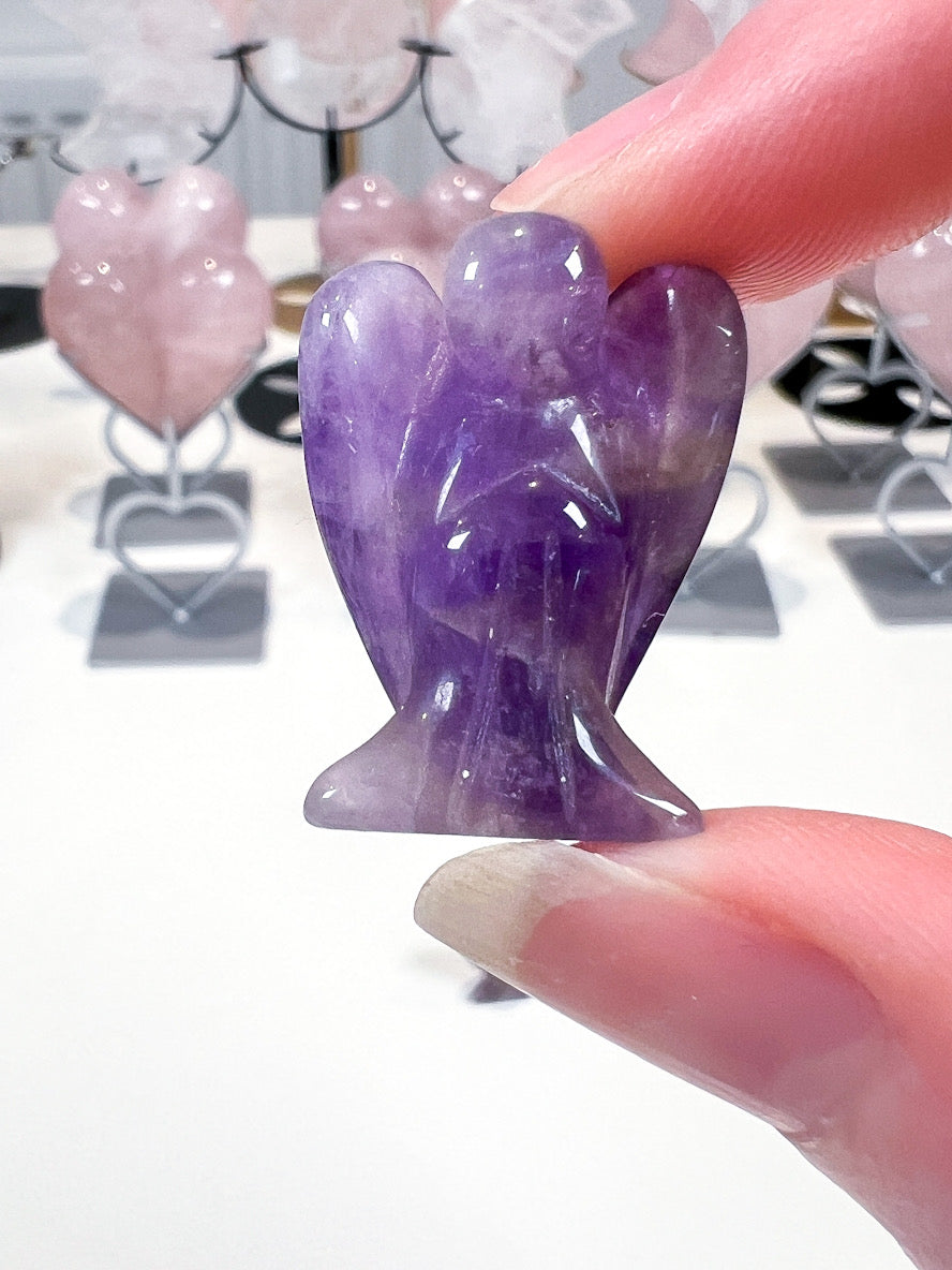 Purple crystal angel figurine held by a hand with blurred background