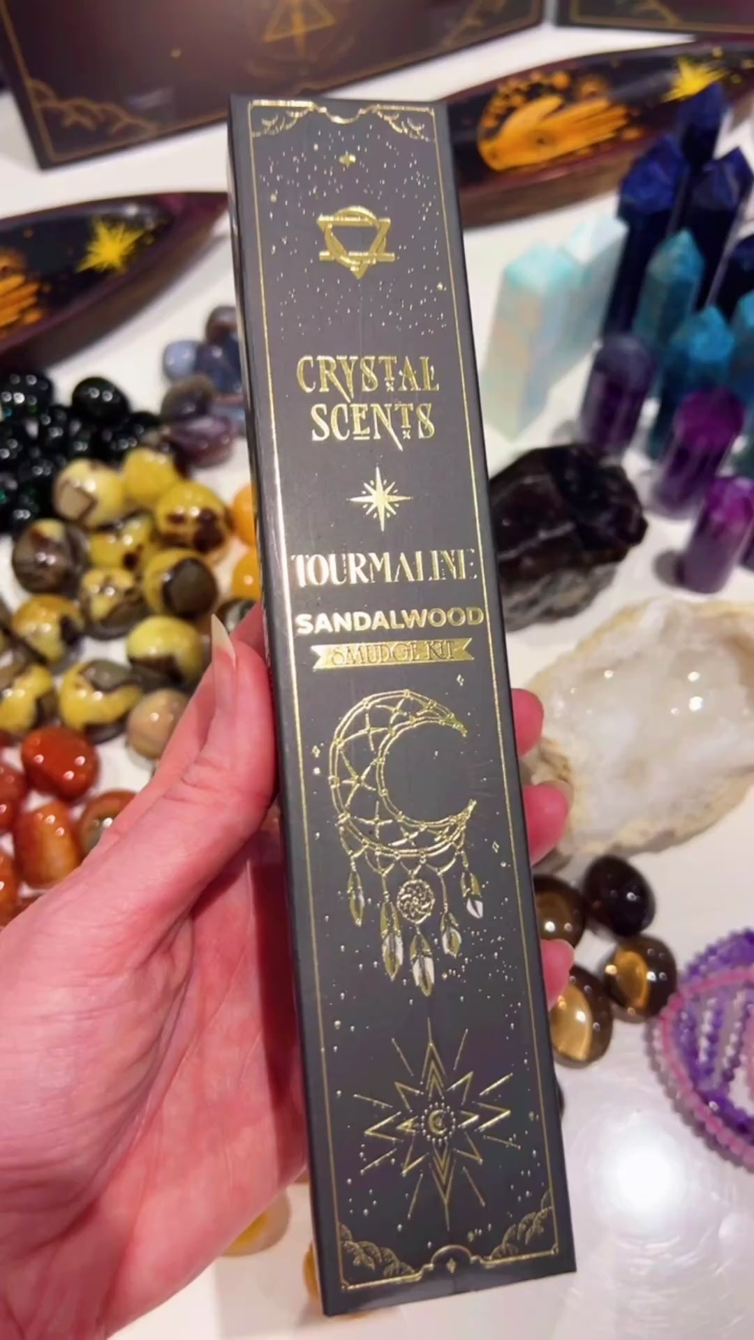 Black Tourmaline Smudge Incense Sandalwood Scented in hand with blurred crystals in the background.