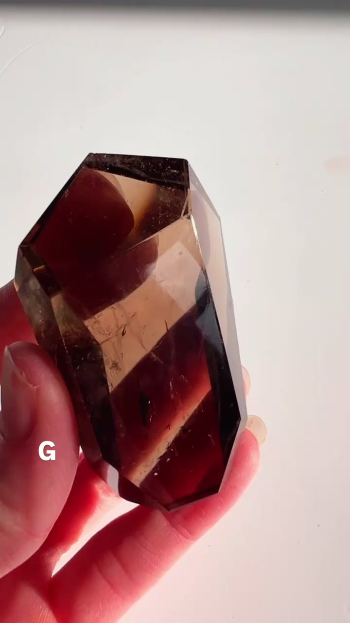 Smoky Quartz free form in hand with a white background.