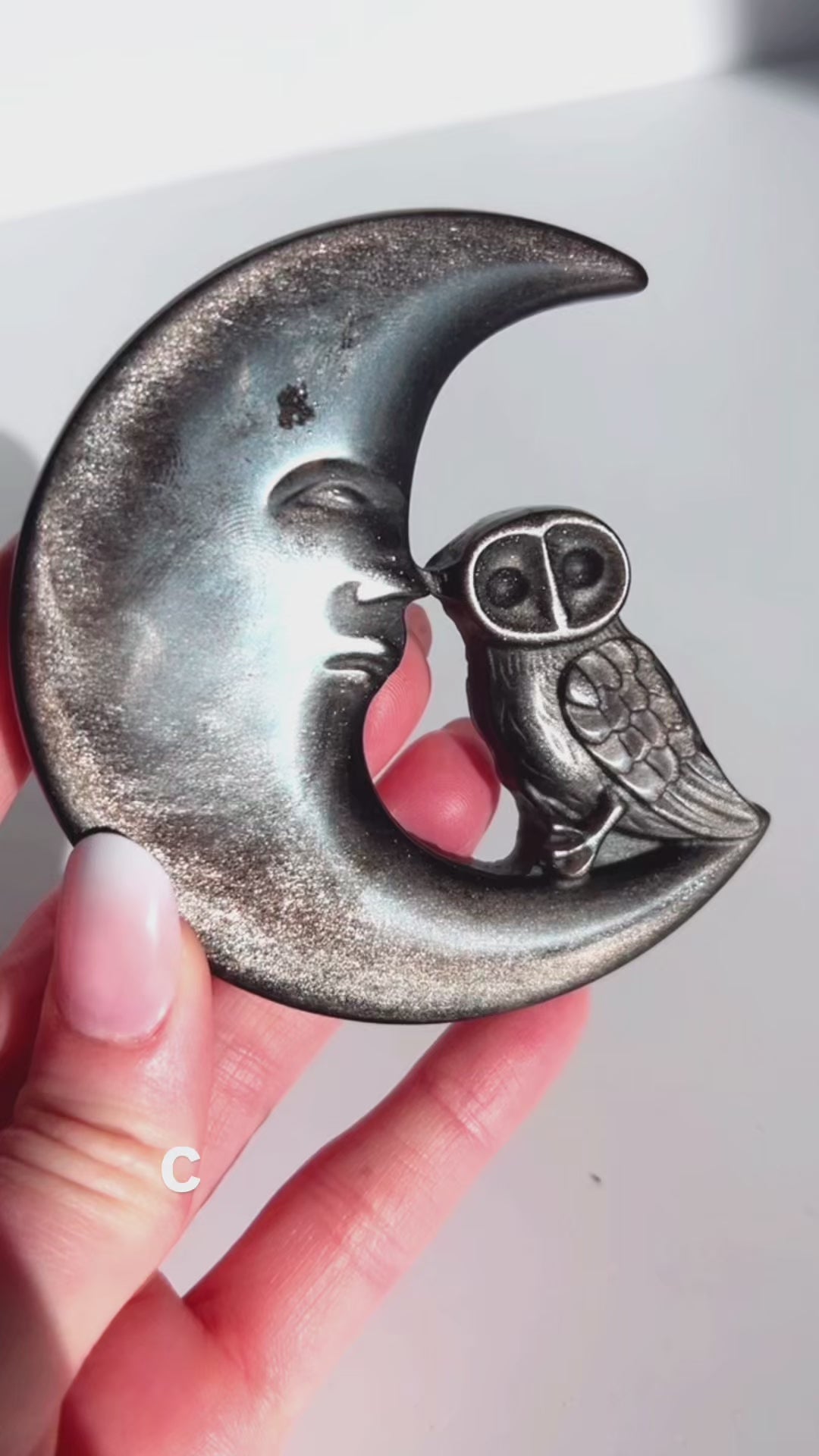 Silver Sheen Obsidian Moon and Owl Carving in hand with white background
