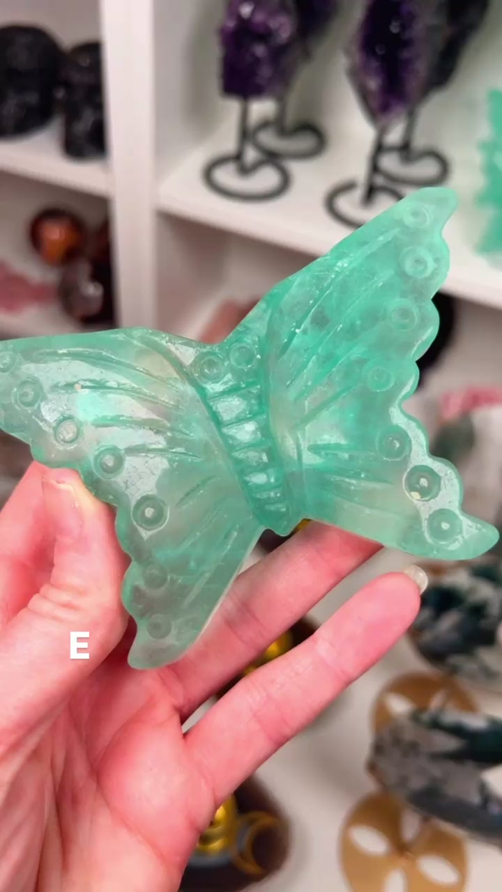 Fluorite butterfly in a hand with crystals in the background.